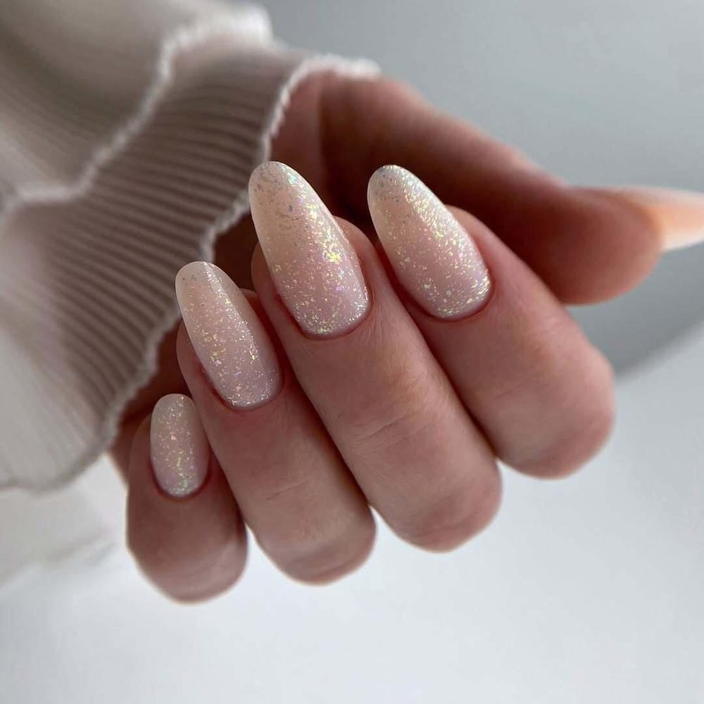 Almond nails with a sheer base and holographic flakes